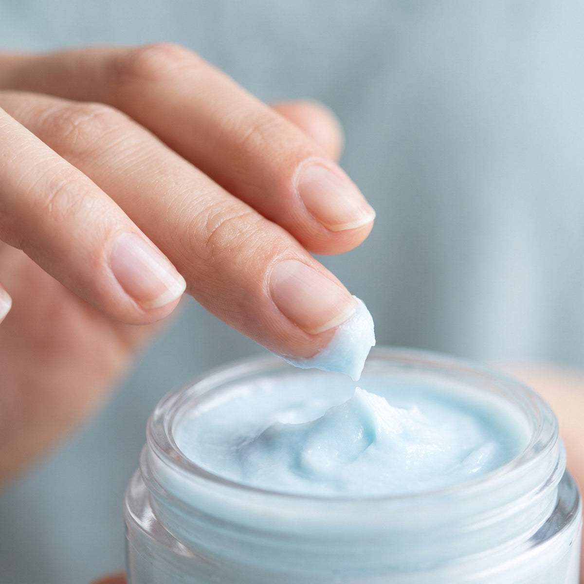 Fingertip lifting a scoop of balm